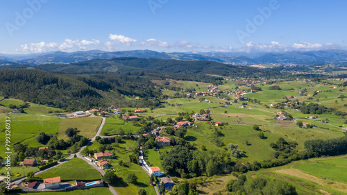 Bild auf Leinwand Landscape of a green valley with houses and mountains on a sunny day