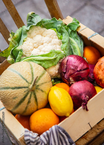 A box of vegetables and fruits outdoors near a street shop, real photo. High quality photo