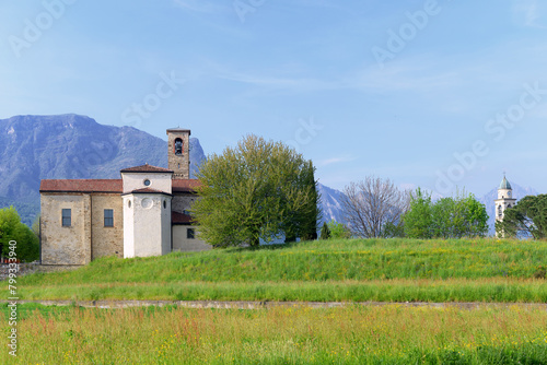 Church of San Giorgio and campanile of the Rosario churh in natural landscape in Annone di Brianza, Italy with mountains and blue sky photo