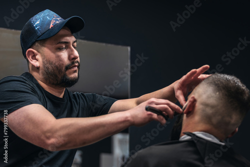 A barber shaves a man's beard. The barber uses a straight razor to shave the man's beard