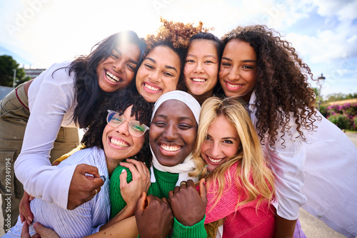 Fotografie Portrait of group of beautiful young multiracial girl friends community hugging and looking at camera outdoor