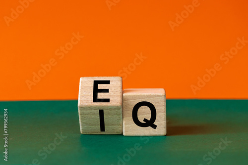 EI or EQ icon. A wooden block with a word showing both the symbol of emotional intelligence and emotional quotient. Beautiful green and orange background, copy space. Psychological and EI or EQ