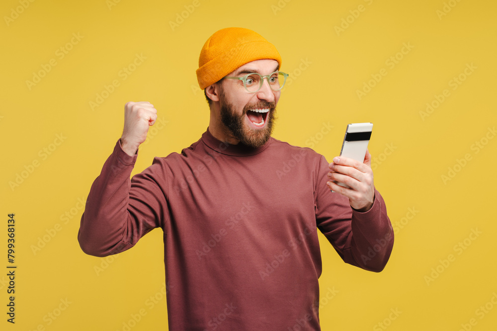Portrait of excited man holding mobile phone, watching video making victory gesture Portrait of excited man holding mobile phone, watching video making victory gesture