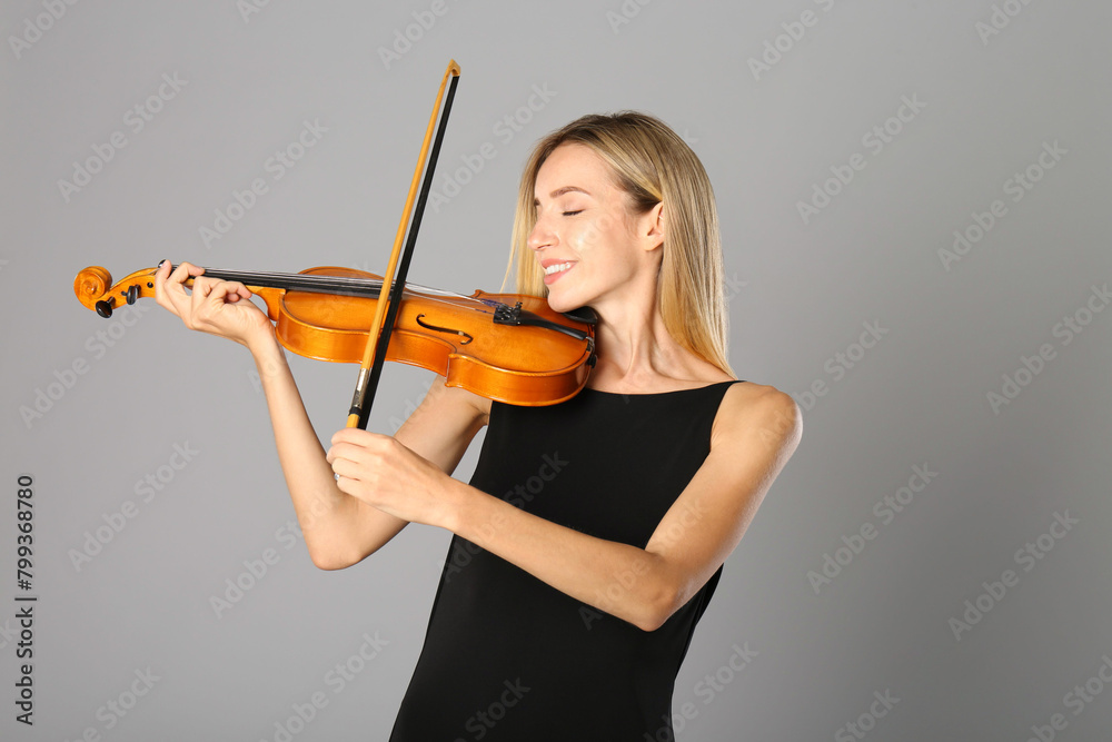 Beautiful woman playing violin on grey background Beautiful woman playing violin on grey background