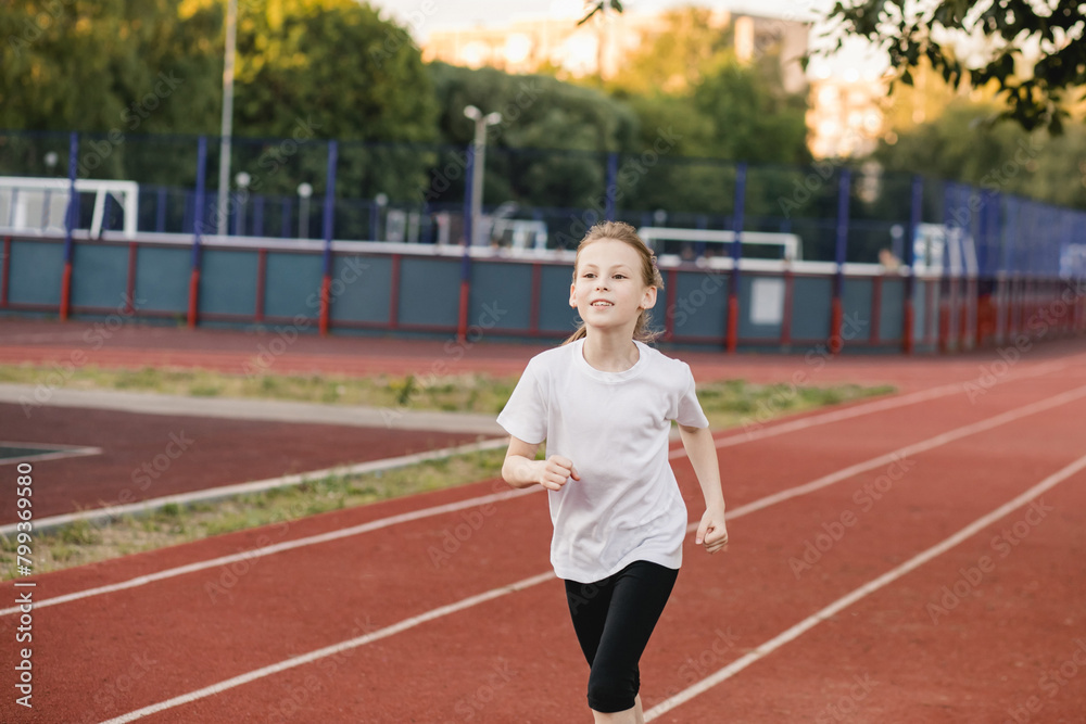 Smiling tween girl runner on a racing track. ?hildren healthy active lifestyle and physical education concept.