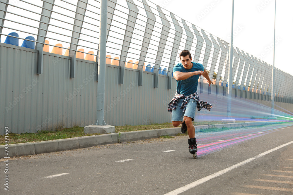Obraz premium Young man roller skating outdoors. Light trails showing his speed