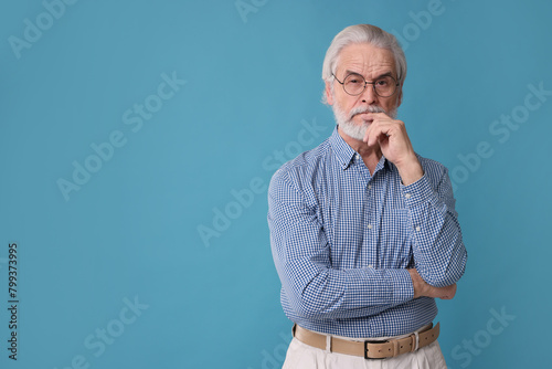 Portrait of stylish grandpa with glasses on light blue background, space for text