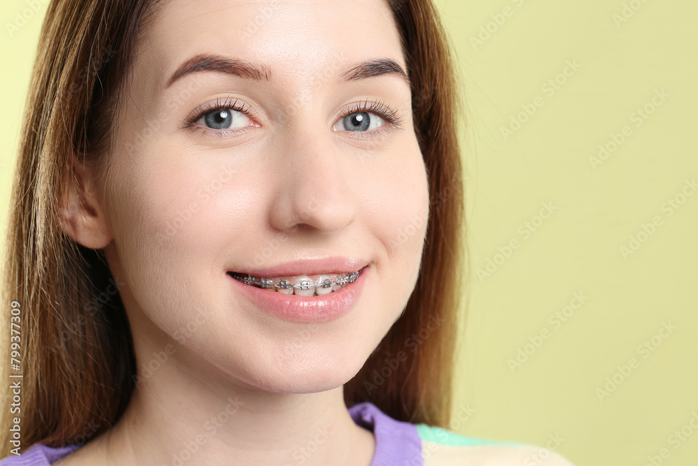 Portrait of smiling woman with dental braces on light green background, closeup. Space for text