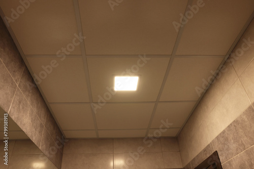 Ceiling with PVC tiles and lighting indoors, low angle view