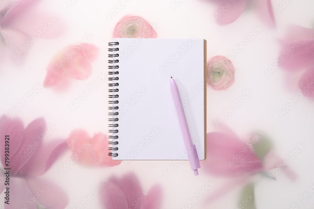 Guest list. Notebook and pen on spring floral background, top view Guest list. Notebook and pen on spring floral background, top view