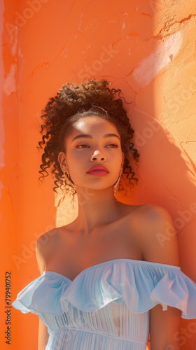 Beautiful young woman in blue dress on orange wall