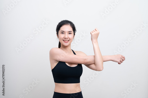 Attractive Asian woman in black workout clothes doing arm stretching on white background. Confident young female athlete body warm up before workout on isolated.