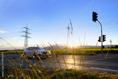 beautiful dramatic landscape, car road visible behind grass, power towers, field in evening in rays sunset, concept beauty of nature, modern energy, technology, seasonal change photo