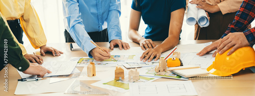 Professional architect engineer team discussion about architectural project on meeting table with wooden block and blueprint scatter around. Design and cooperate concept. Closeup. Delineation. photo
