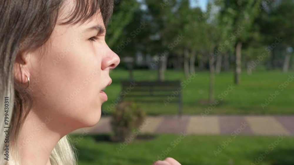 An inhaler during walking. A view of stressed teen girl hold her inhaler and use it because of allergy attack in the garden. An inhaler during walking. A view of stressed teen girl hold her inhaler and use it because of allergy attack in the garden.