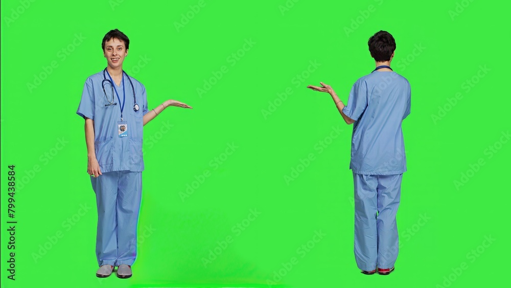 Medical assistant pointing at something aside and doing web commercial, creating advertisement against greenscreen backdrop. Young nurse with scrubs showing a thing to left or right sides. Camera A. Medical assistant pointing at something aside and doing web commercial, creating advertisement against greenscreen backdrop. Young nurse with scrubs showing a thing to left or right sides. Camera A.