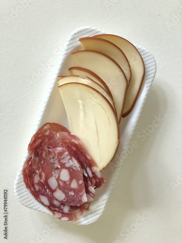 delicious smoked cheese slices and hard smoked sausage with lard on a plate, top view