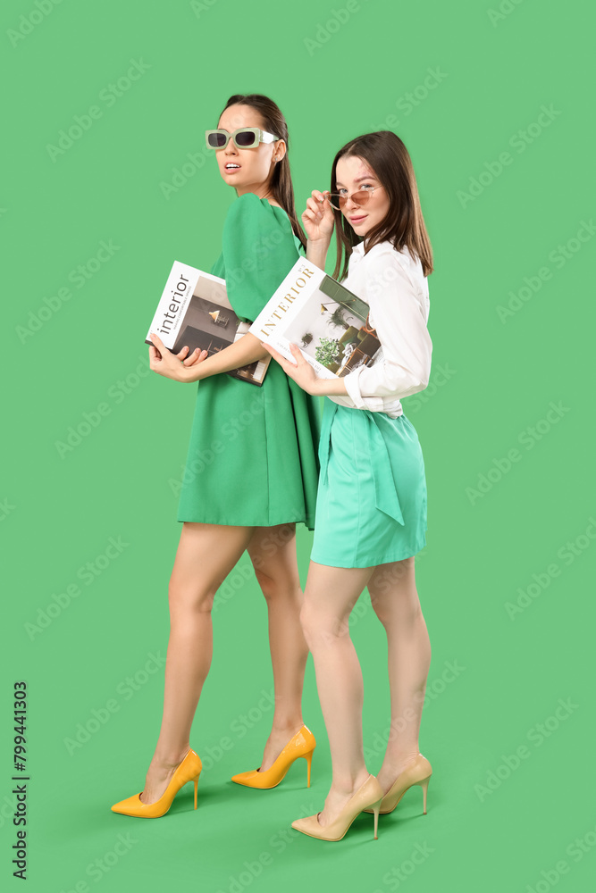 Stylish young women with magazines on green background Stylish young women with magazines on green background