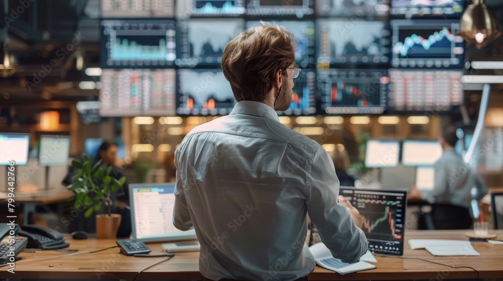 Focused Financial Analyst Analyzing RealTime Trading Data in Busy Office Environment Stock Photo Focused Financial Analyst Analyzing RealTime Trading Data in Busy Office Environment Stock Photo