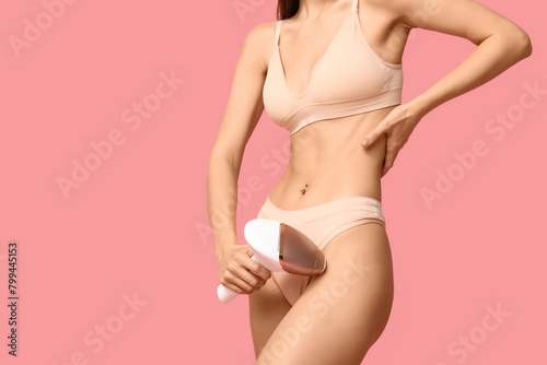 Young woman with modern photoepilator on pink background
