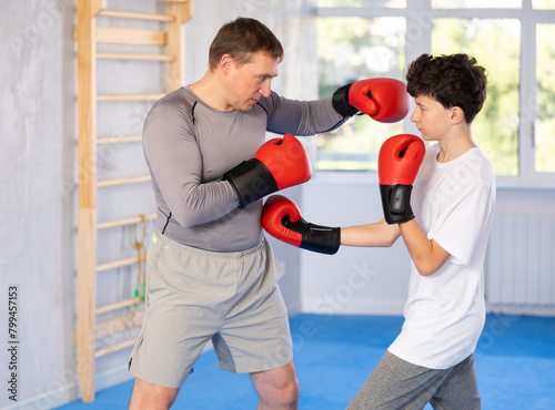 Father teaches son to box during individual boxing training in the gym