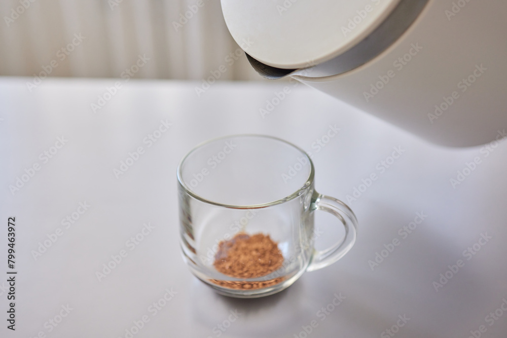 Woman stirs instant coffee in glass mug with boiled water on grey stone table Woman stirs instant coffee in glass mug with boiled water on grey stone table