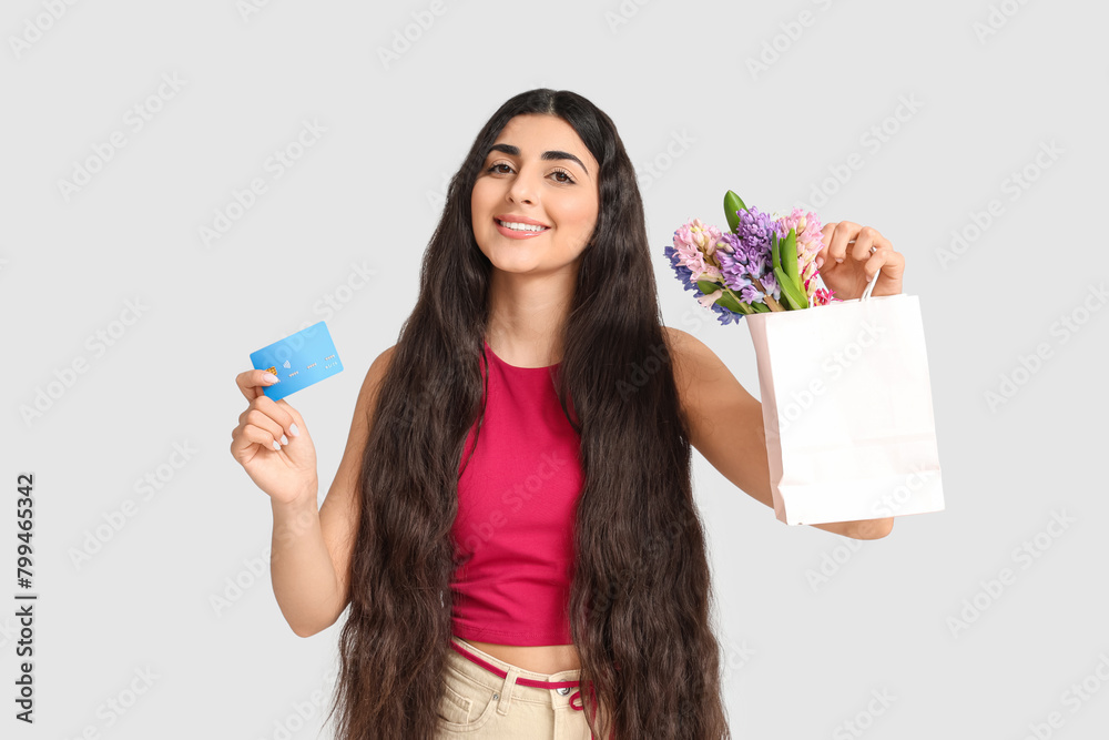 Happy smiling young woman holding paper bag with hyacinth flowers and credit card on white background Happy smiling young woman holding paper bag with hyacinth flowers and credit card on white background