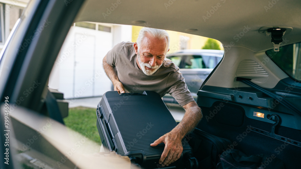 Obraz premium One senior man travel concept male put suitcase in trunk of the car