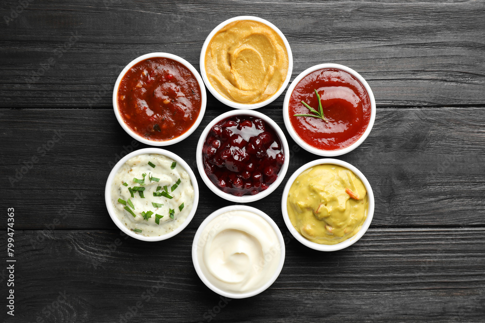 Different tasty sauces in bowls on black wooden table, flat lay Different tasty sauces in bowls on black wooden table, flat lay
