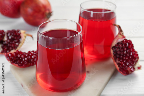 Tasty pomegranate juice in glasses and fresh fruits on white wooden table, closeup
