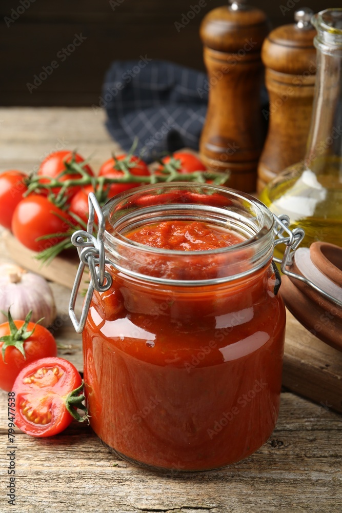 Homemade tomato sauce in jar and fresh ingredients on wooden table, closeup Homemade tomato sauce in jar and fresh ingredients on wooden table, closeup