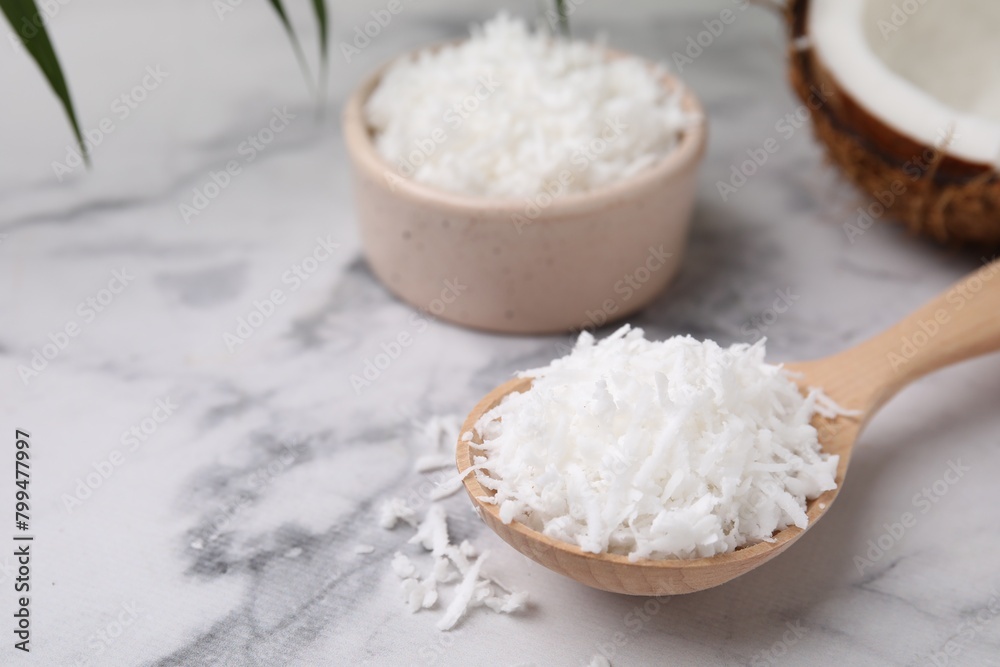 Coconut flakes in wooden spoon on white marble table, closeup. Space for text Coconut flakes in wooden spoon on white marble table, closeup. Space for text