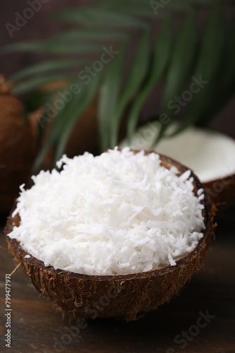 Coconut flakes in nut shell on wooden table