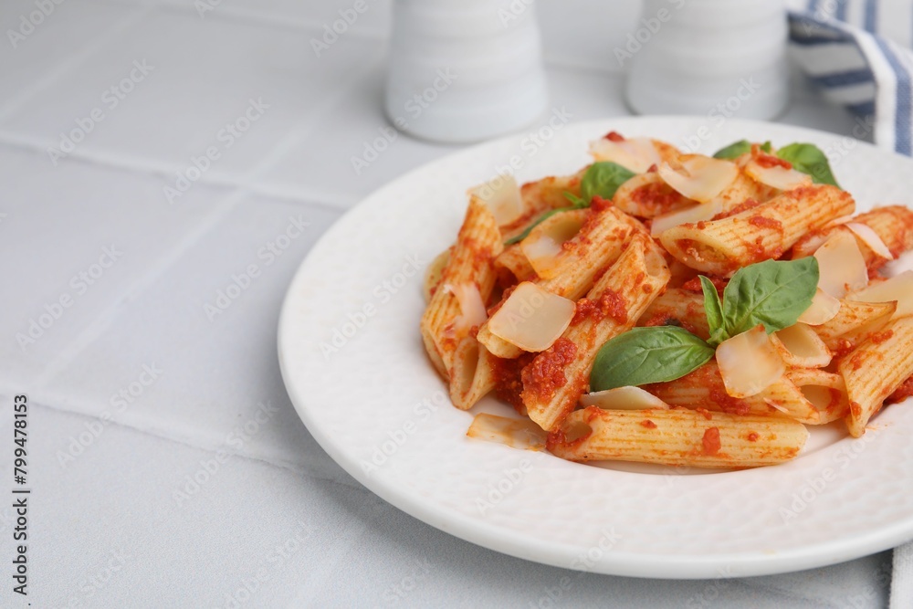 Tasty pasta with tomato sauce, cheese and basil on white tiled table