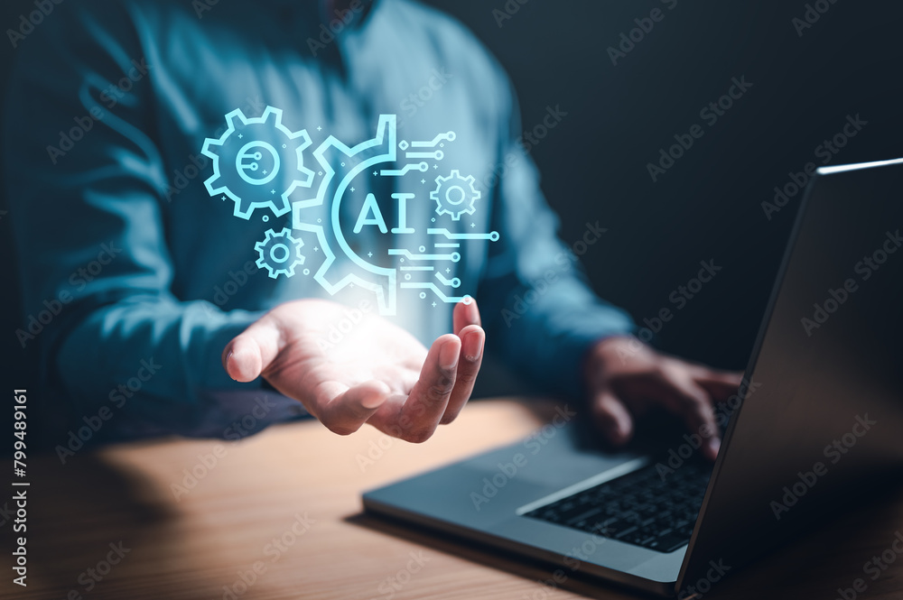 iot, machine, artificial, ai, brain, strategy, intelligence, robot, learning, innovation. A man is holding a laptop with a blue screen that has a picture of gears and the word AI. iot, machine, artificial, ai, brain, strategy, intelligence, robot, learning, innovation. A man is holding a laptop with a blue screen that has a picture of gears and the word AI.