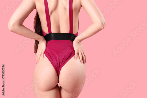 Beautiful young woman in swimsuit on pink background