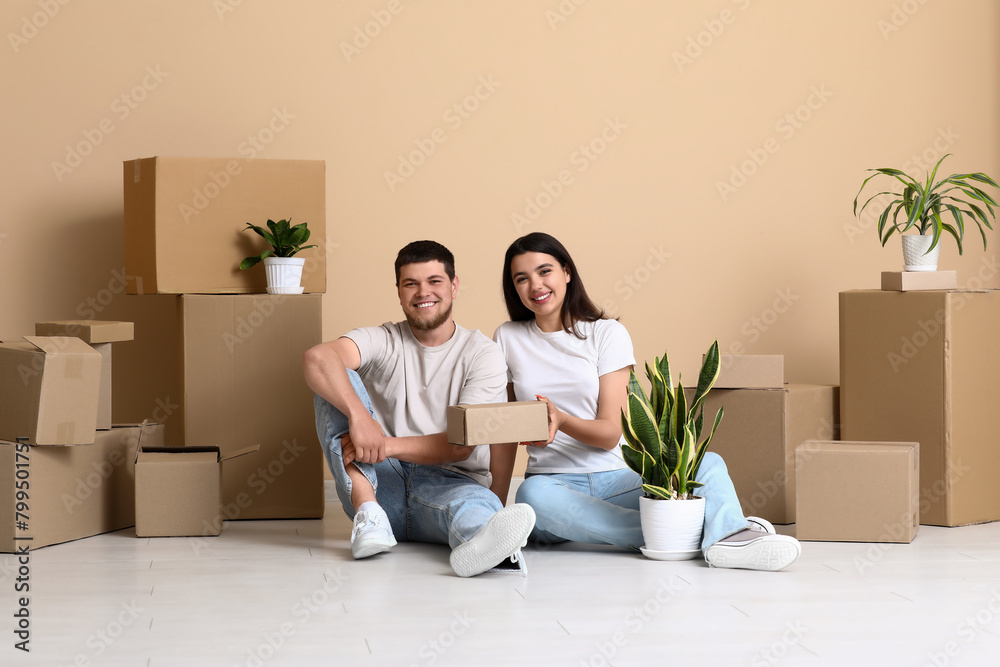 Young happy couple sitting and unpacking belongings in their new house