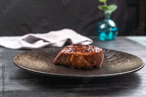 Fresh juicy delicious beef steak on a dark background. Meat dish with spices and herbs