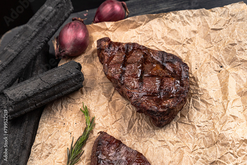 Fresh juicy delicious beef steak on a dark background. Meat dish with spices and herbs