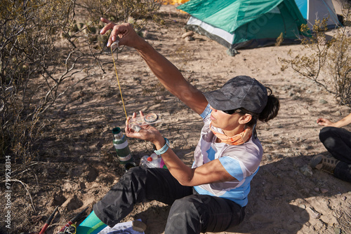 Woman hiker sitting at her campsite with a baseplate orienteering compass, orienting herself, taking a bearing, analyzing the course of her next hike.