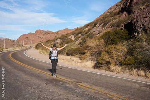 Woman hiker opening her arms in the middle of the road  carefree  happy  living an adventure during her vacations in the mountains of Potrerillos  Mendoza  Argentina.