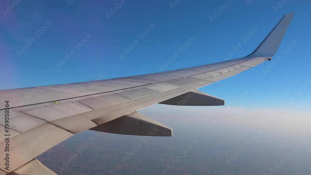 Wing of a flying plane on a background of blue sky and clouds.