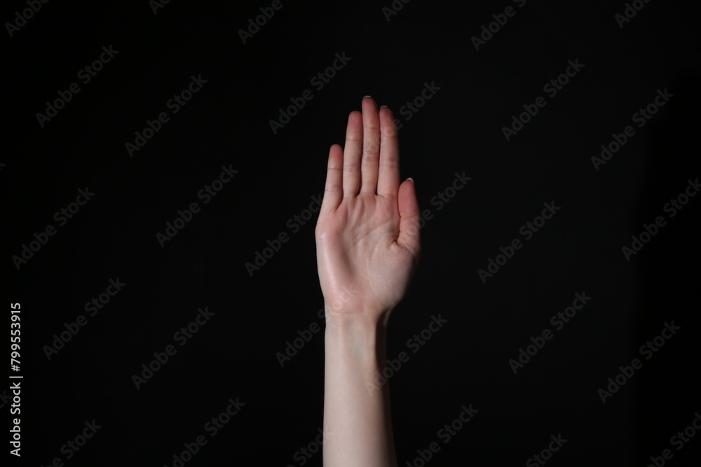 Woman showing open palm on black background, closeup Woman showing open palm on black background, closeup