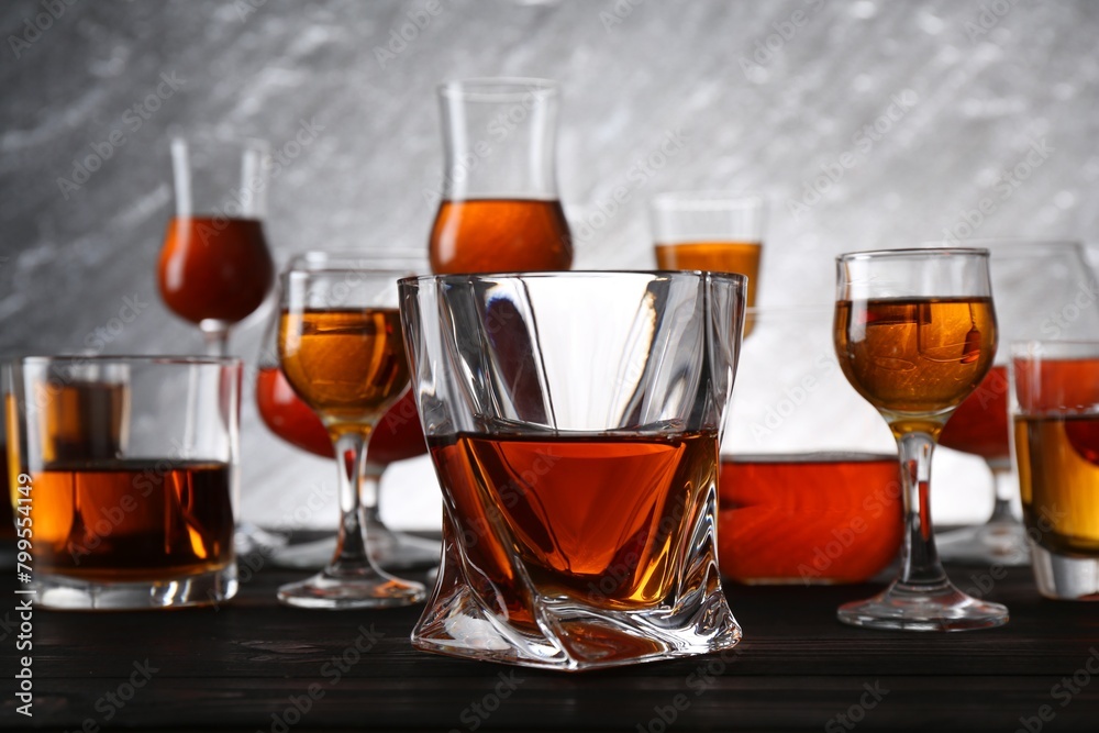 Different delicious liqueurs in glasses on dark wooden table Different delicious liqueurs in glasses on dark wooden table