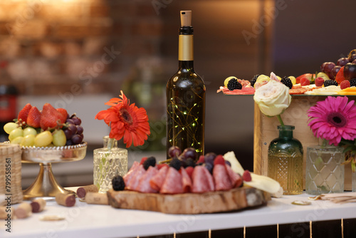 Cheese, wine, cold meats, grapes and flowers table with elegant decorations