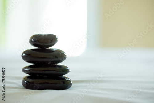 Balanced perfectly in a spa environment  a stack of smooth black stones creates tranquil atmosphere  enhancing the sense of focus and relaxation