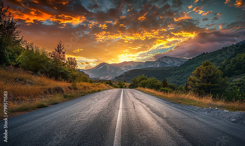 Low angle view of the evening sunset shining softly on a mountain with a paved road passing through it. 