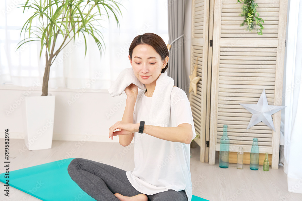 © siro46 - 自宅でエクササイズ中にスマートウォッチを使う女性
