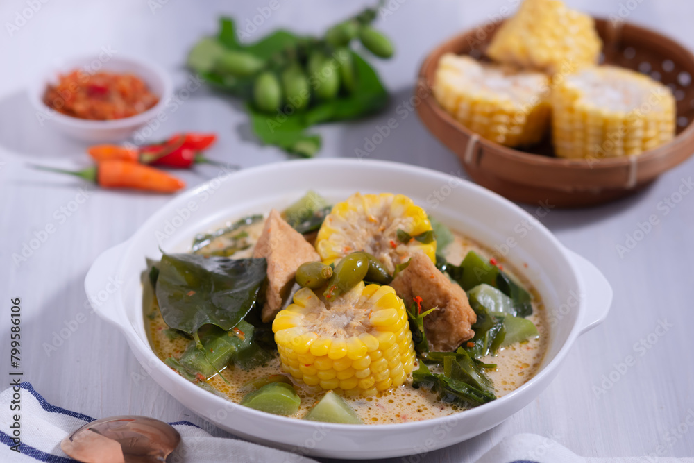 Fototapeta premium Sayur Lodeh is a vegetable dish made with coconut milk that is typical of Indonesia, especially in Central Java and DI Yogyakarta. Served in a bowl on a white table. Selective focus.