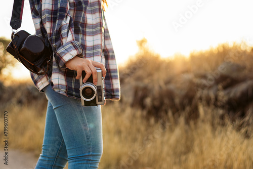Unrecognizable woman taking photos with analog camera in the countryside photo